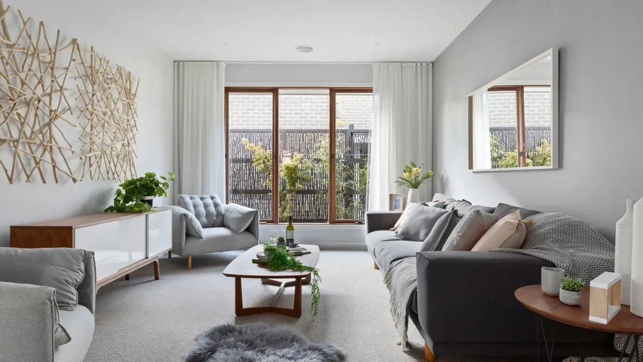 Salones en gris y beige con sofá oscuro, sillón acogedor, mesa de centro de madera y decoración natural.