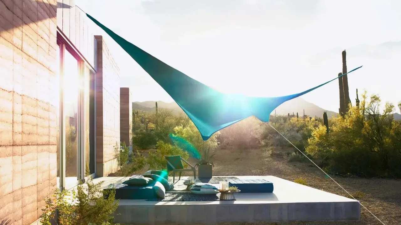 Ideas de sombra para terraza desértica: una vela azul crea un oasis fresco sobre cojines y un sillón.