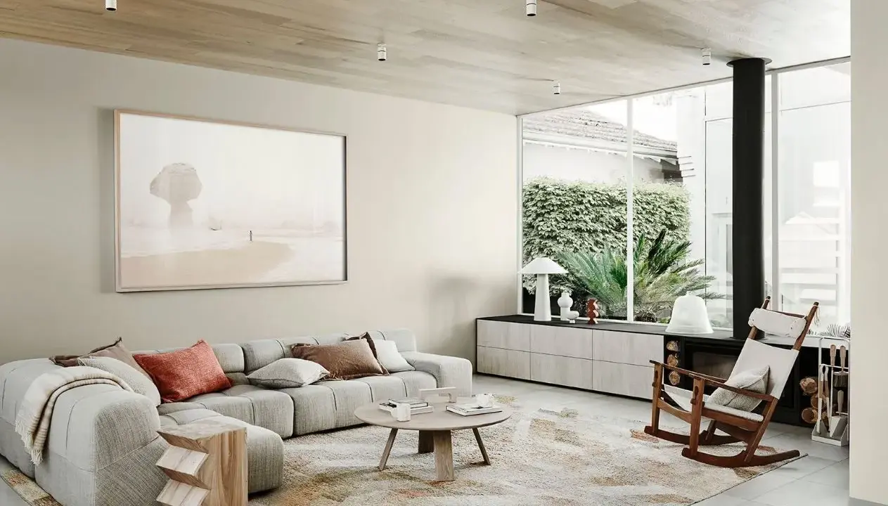 Salón moderno con sofá modular gris, alfombra abstracta y arte de playa. Muestra todos los estilos de decoración de interiores.