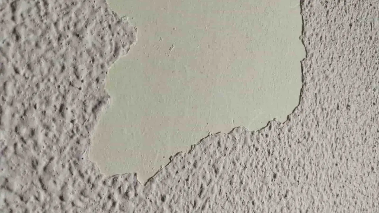 Detalle de pared con gotelé descascarillado, mostrando la capa inferior lisa. Ideal para aprender como quitar gotele.