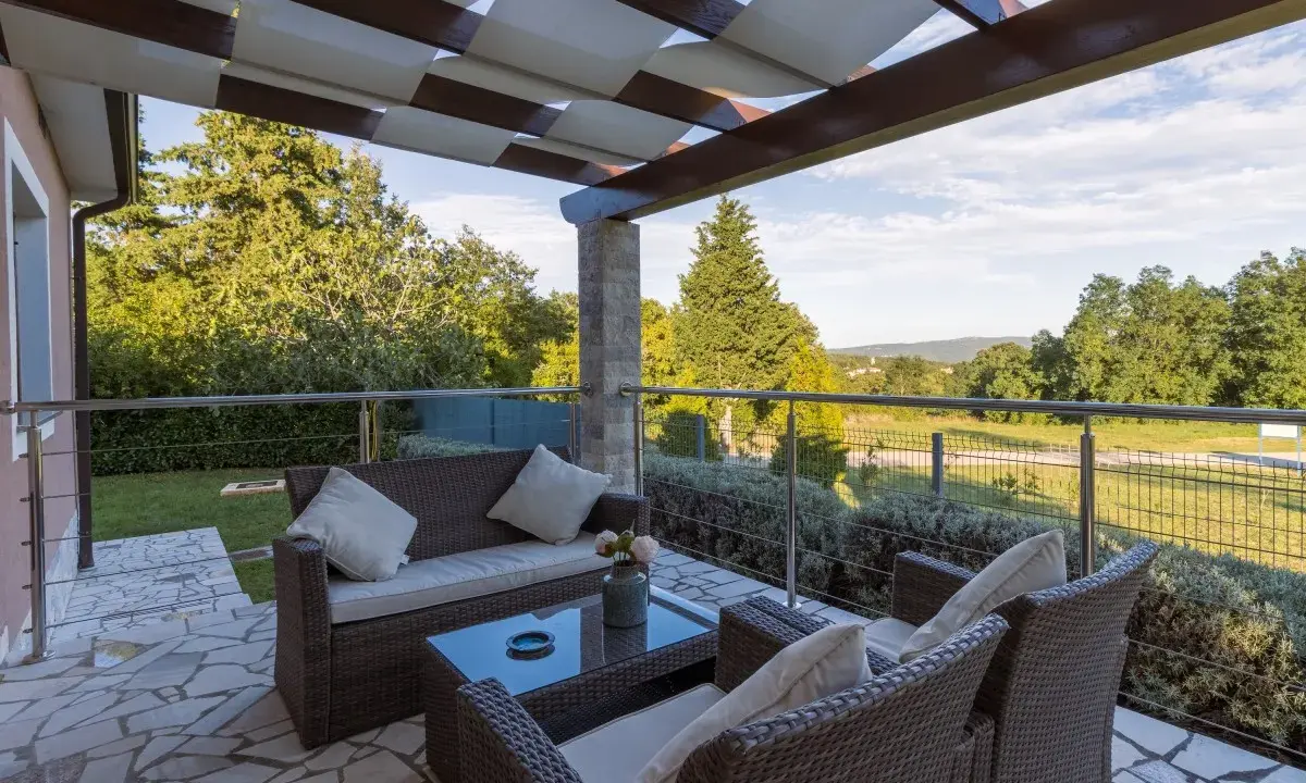Muebles de mimbre y mesa de cristal en una terraza grande con vistas al campo. Ideas para como decorar una terraza grande con estilo y comodidad.