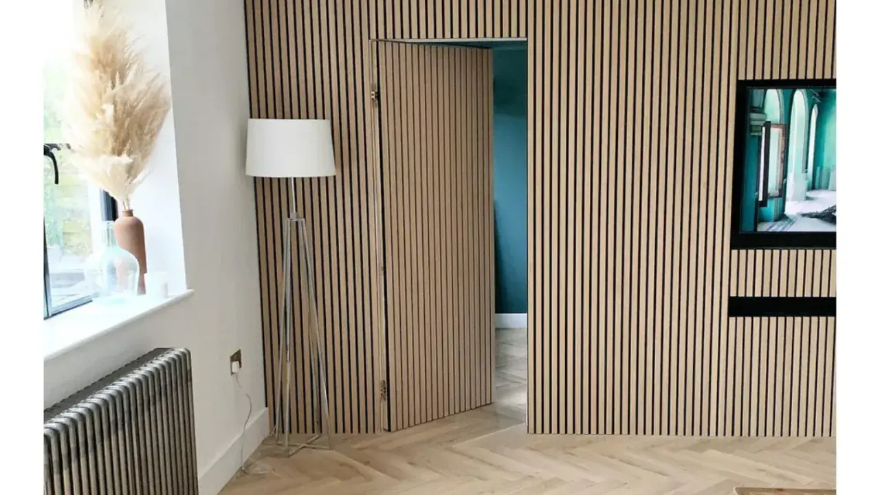 Una puerta oculta en una pared revestida de lamas de madera, una solución ingeniosa para como ocultar una puerta en una pared.