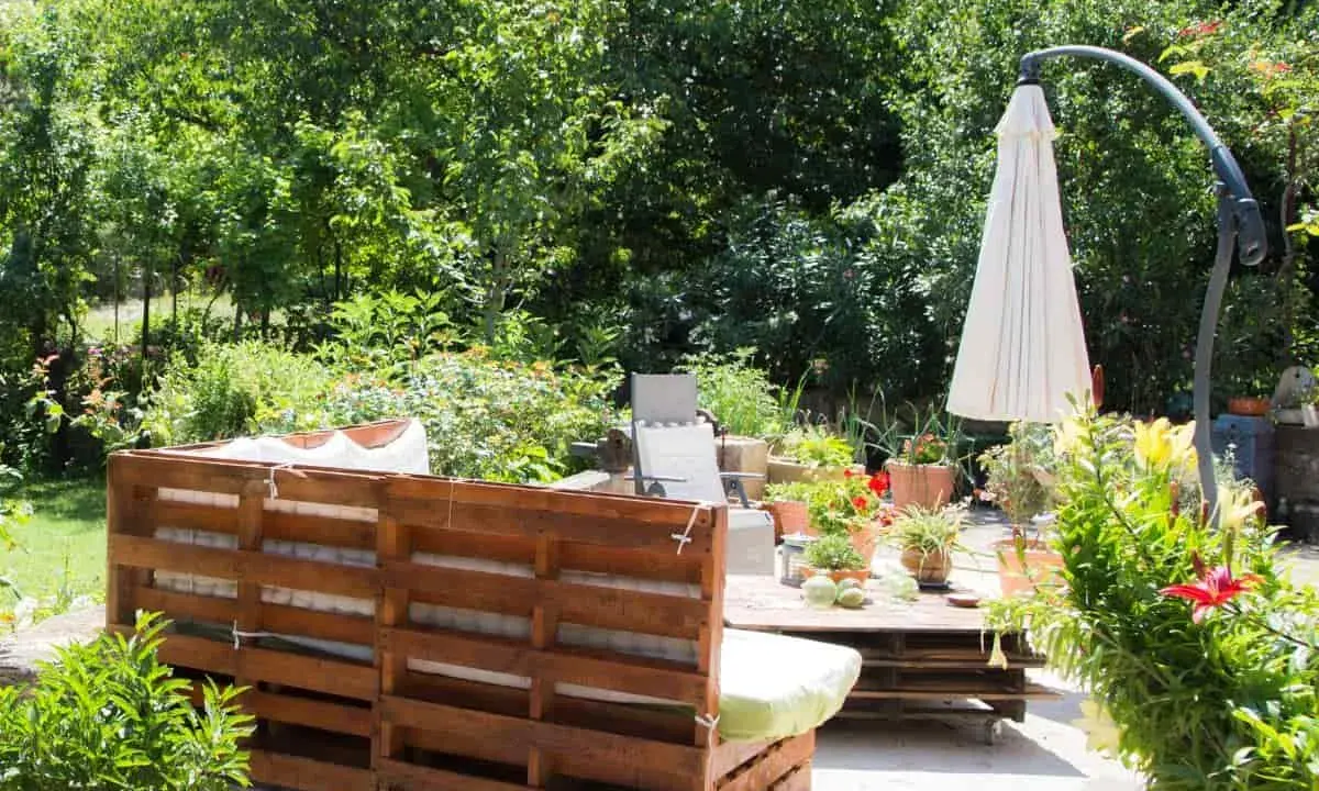 Un rincón acogedor en el jardín, con muebles de palets y plantas exuberantes. Ideal para una zona chill out.
