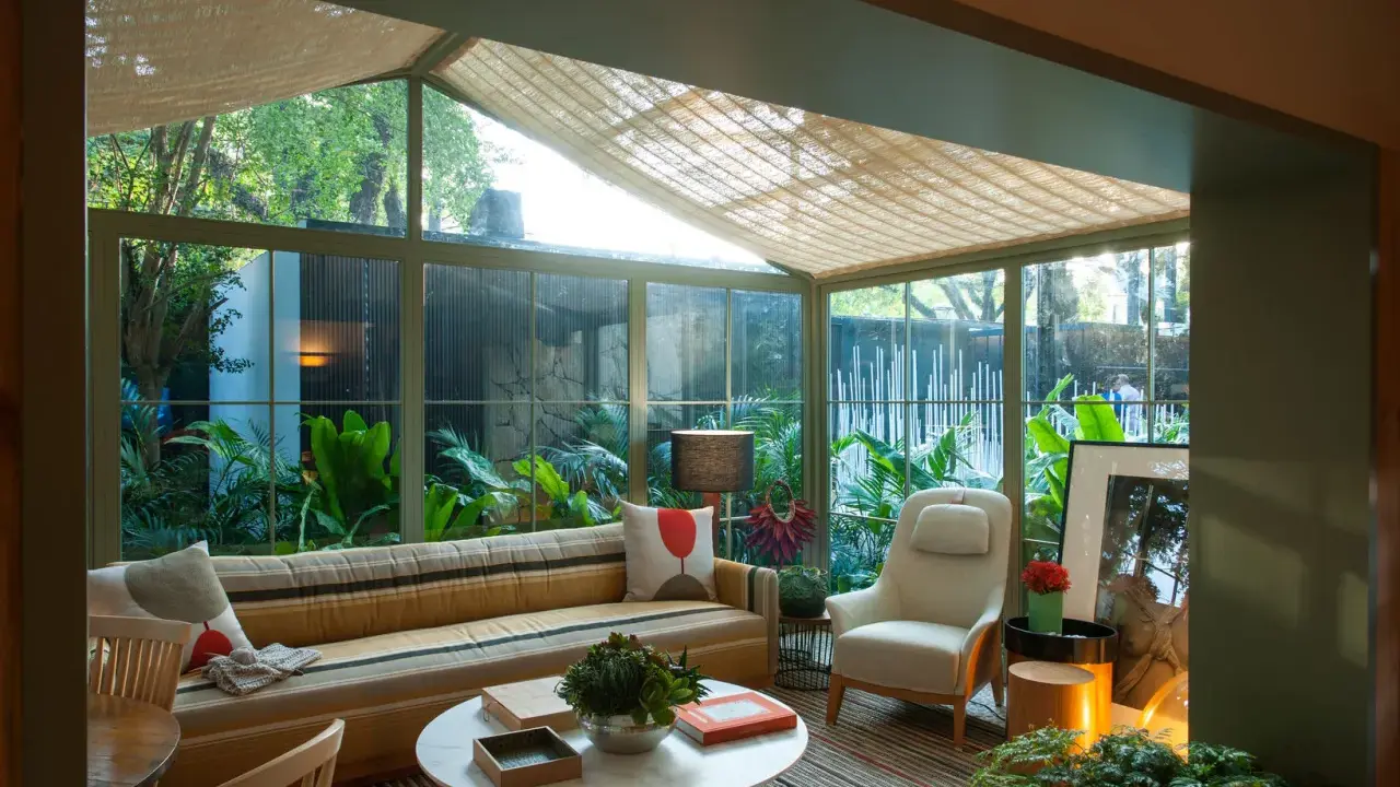 Acogedor solarium terraza con sofá a rayas, sillón, mesa de centro y exuberante vegetación.