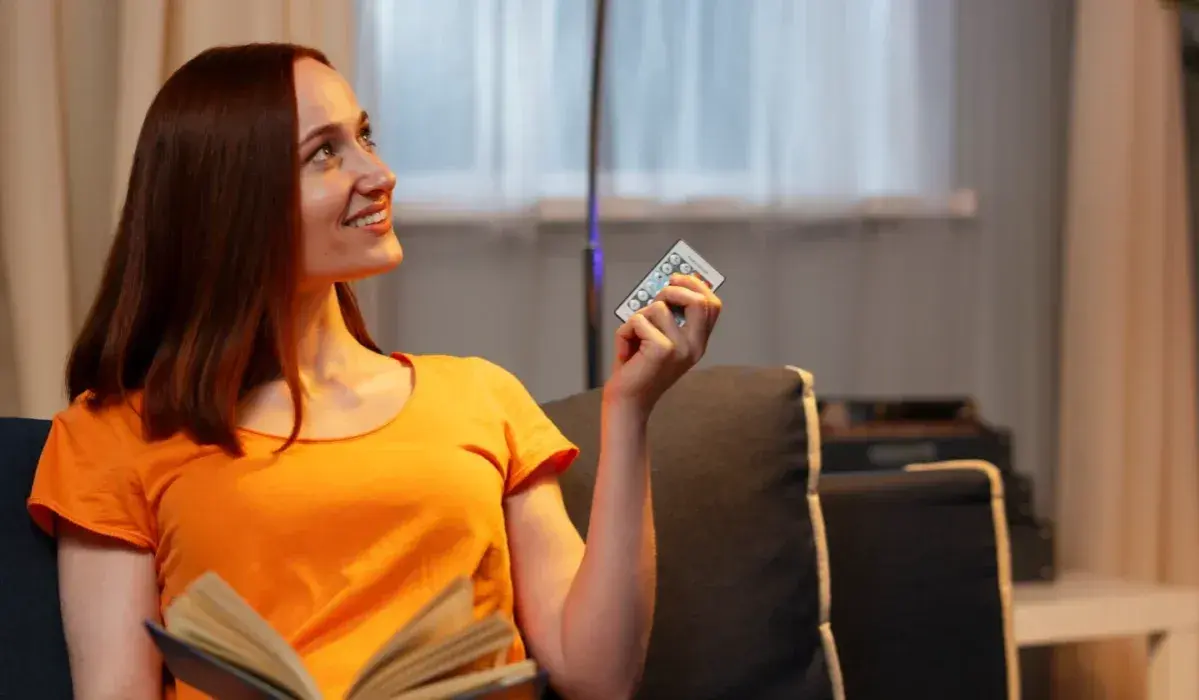 Mujer sonríe con un control remoto en mano, pensando que 800 kWh es mucho para su factura de luz.