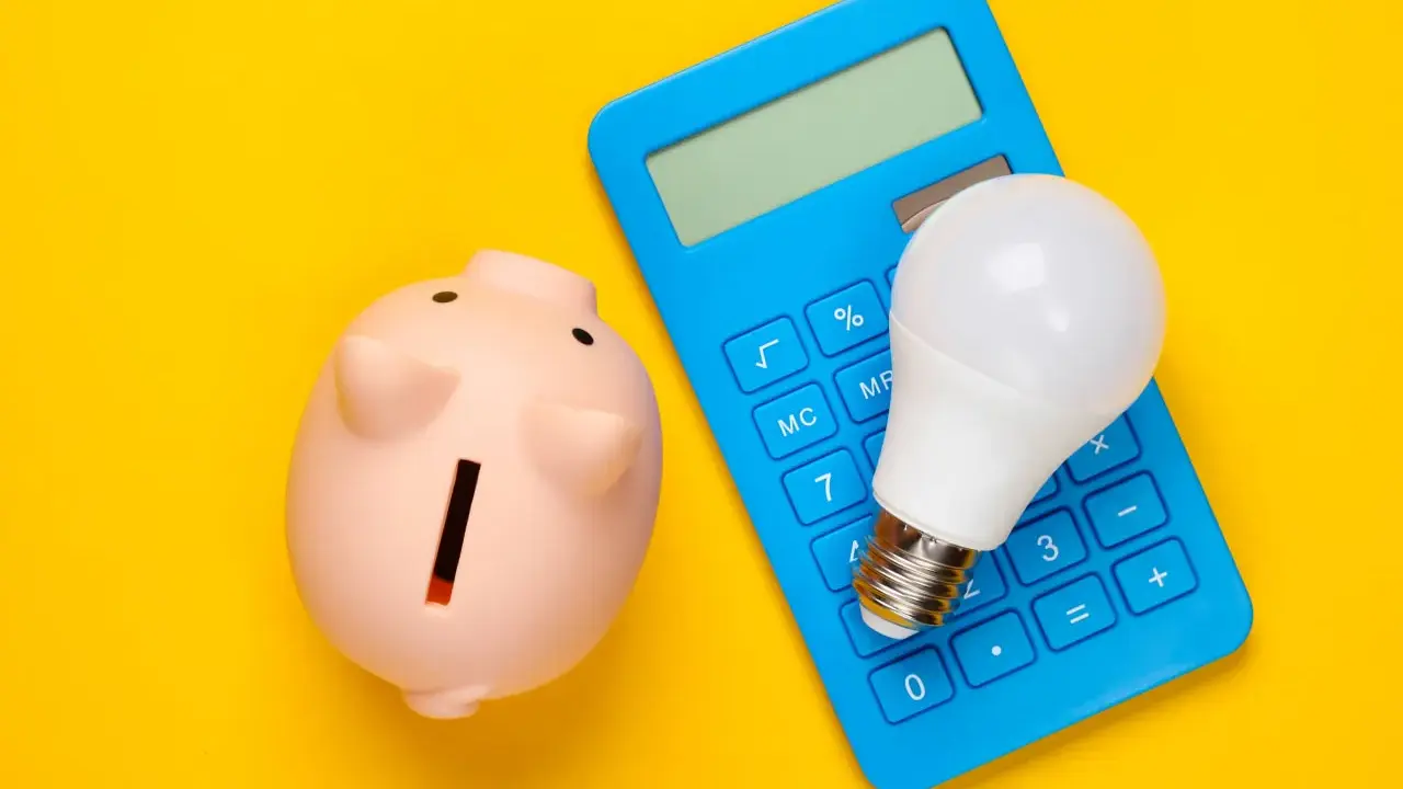 Hucha rosa, calculadora azul y bombilla LED. Ideas para como ahorrar en la factura del gas y la luz.