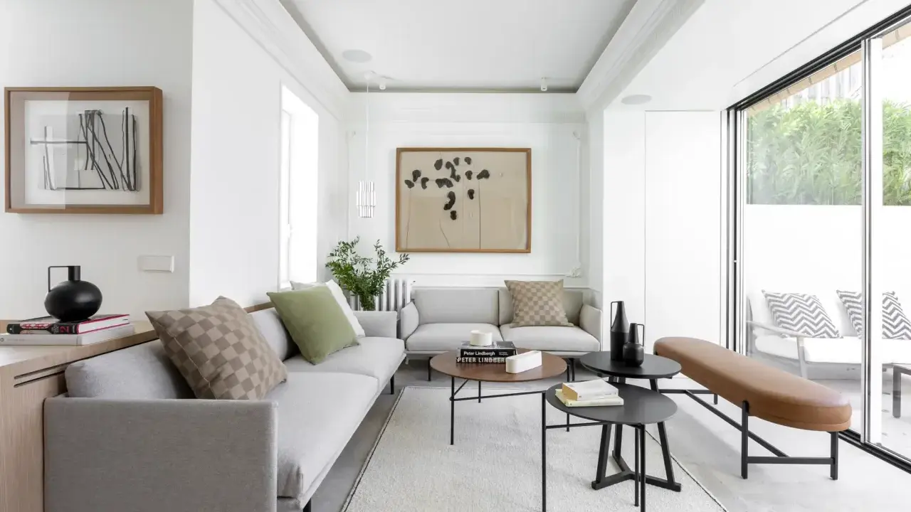 Salón moderno con sofás grises, mesas bajas y acceso directo a una terraza, creando un espacio fluido para unir terraza y salón.