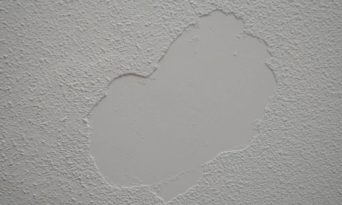 Parche de yeso liso sobre pared con gotelé, listo para lijar y unificar la textura.