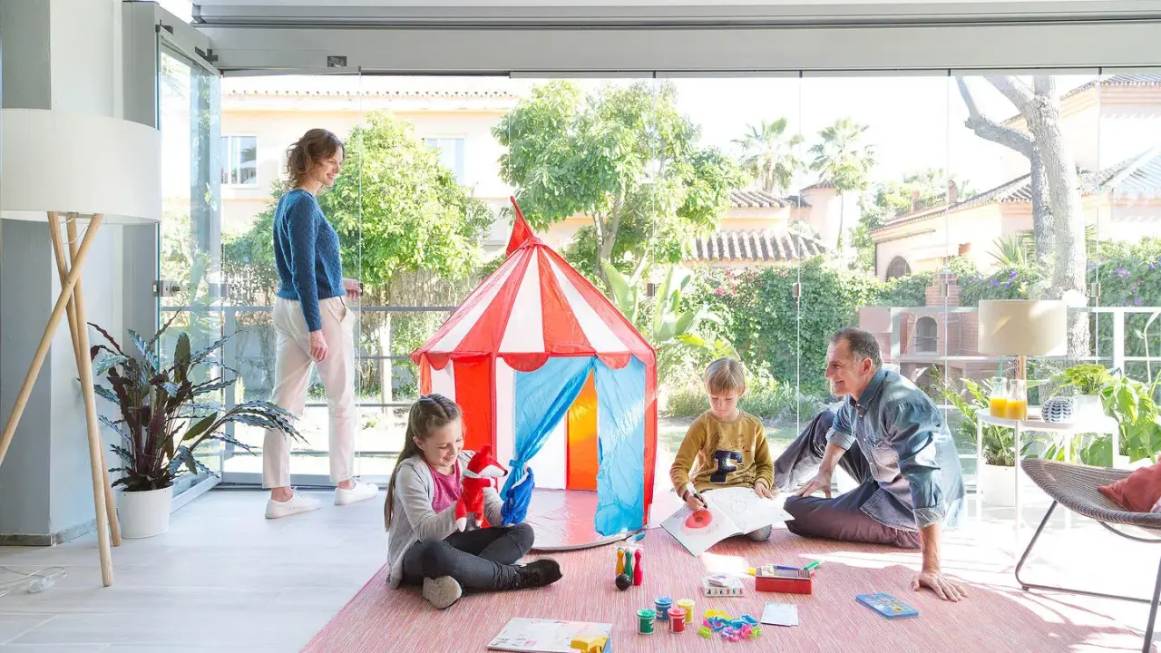 Familia divirtiéndose en una terraza decorada para niños con una carpa de circo y juegos.