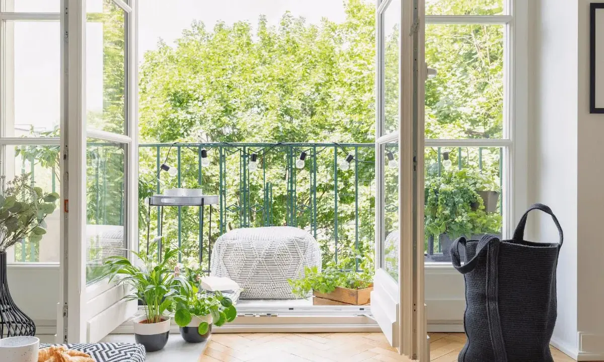 Balcones con plantas verdes y luces decorativas, invitando a disfrutar del exterior desde un acogedor interior.