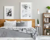 Dormitorio moderno con cama de madera, cuadros botánicos y estantería. Los tonos grises para paredes interiores crean un ambiente sereno y elegante.