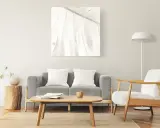 Un cuadro de hoja en tonos claros decora la pared, complementando el estilo zen de los cuadros feng shui dormitorio. Sofá gris, sillón blanco y mesa de centro de madera.