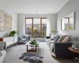 Salones en gris y beige con sofá oscuro, sillón acogedor, mesa de centro de madera y decoración natural.