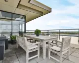 Mesa de madera y sillas en una terraza con vistas al cielo azul.