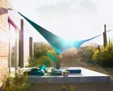 Ideas de sombra para terraza desértica: una vela azul crea un oasis fresco sobre cojines y un sillón.