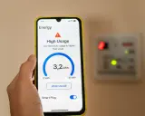 Un teléfono muestra cómo se mide el consumo eléctrico con 3,2 kWh y alerta de alto uso.