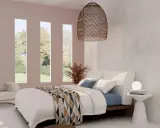 Acogedora habitación blanca y beige con cama confortable, sillón y vistas al jardín a través de ventanas verticales.