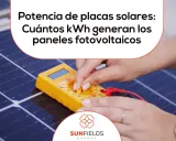 Manos ajustando un multímetro sobre una placa fotovoltaica, midiendo su potencia.