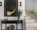 Entrada de una casa pequeña con consola negra, cuadro de tiza y escaleras. Un toque de feng shui casa pequeña para armonizar el espacio.