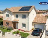 Casa moderna con paneles solares en el tejado, promoviendo el ahorro con paneles solares. Jardín cuidado y coche aparcado.