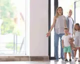 Familia de 4 miembros sonriendo y entrando a su nuevo hogar, pensando en el consumo medio electricidad.