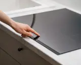 Mano ajustando la placa de inducción, pensando en el consumo energético.