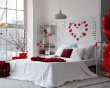 Un dormitorio decorado con un estilo romántico, lleno de corazones rojos y globos, ideal para San Valentín.