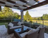 Muebles de mimbre y mesa de cristal en una terraza grande con vistas al campo. Ideas para como decorar una terraza grande con estilo y comodidad.