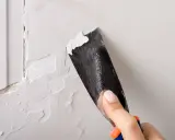 Raspando pintura vieja para preparar la pared. Paso clave para como pintar una pared ya pintada de otro color.