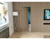 Una puerta oculta en una pared revestida de lamas de madera, una solución ingeniosa para como ocultar una puerta en una pared.