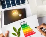 Calculadora muestra "SAVE". Hoja con etiqueta energética y bombilla. ¿Cuánto consume un ordenador en euros?