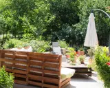 Un rincón acogedor en el jardín, con muebles de palets y plantas exuberantes. Ideal para una zona chill out.