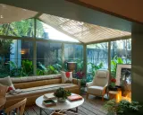 Acogedor solarium terraza con sofá a rayas, sillón, mesa de centro y exuberante vegetación.