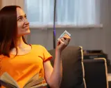 Mujer sonríe con un control remoto en mano, pensando que 800 kWh es mucho para su factura de luz.