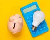 Hucha rosa, calculadora azul y bombilla LED. Ideas para como ahorrar en la factura del gas y la luz.
