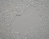 Parche de yeso liso sobre pared con gotelé, listo para lijar y unificar la textura.