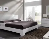 Habitación con muebles blancos y color pared neutro. Cama moderna, mesitas de noche, cómoda y espejo.
