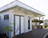 Una cabaña de madera con terraza, ideal para hacer una habitación en una terraza. Luces decorativas cuelgan del techo.