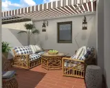 Acogedora decoracion patio interior con muebles de mimbre, cojines a cuadros y un toldo a rayas.