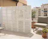 Modernos bloques de hormigón blanco crean un separador de ambiente, una de las mejores tapar balcon ideas. Un sillón y plantas completan el espacio.