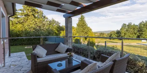 Muebles de mimbre y mesa de cristal en una terraza grande con vistas al campo. Ideas para como decorar una terraza grande con estilo y comodidad.