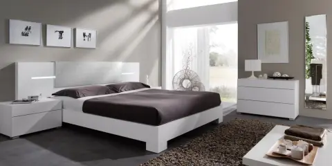 Habitación con muebles blancos y color pared neutro. Cama moderna, mesitas de noche, cómoda y espejo.