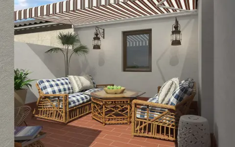 Acogedora decoracion patio interior con muebles de mimbre, cojines a cuadros y un toldo a rayas.