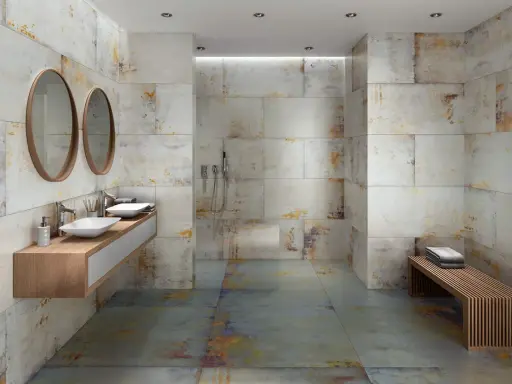 Baño moderno con paredes y suelo de baldosas grises y oxidadas. Los tonos tierra y dorados de las baldosas muestran que colores combinan con el gris en un baño.