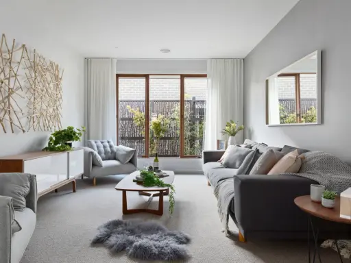 Salones en gris y beige con sofá oscuro, sillón acogedor, mesa de centro de madera y decoración natural.