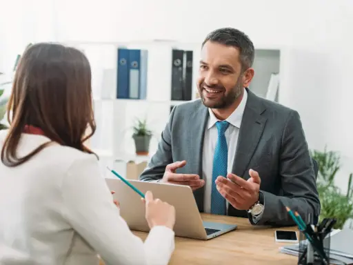 Un hombre sonriente, que parece ser un asesor energético, explica algo a una mujer en una oficina.