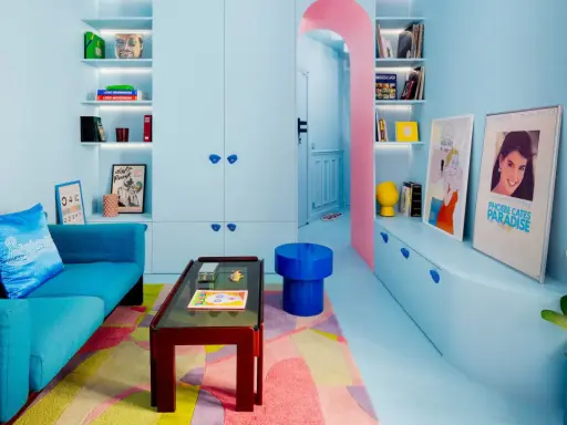 Salón pequeño con sofá azul, alfombra geométrica y estanterías llenas de objetos. Los colores pastel y vibrantes son ideales como colores para pintar salones pequeños.