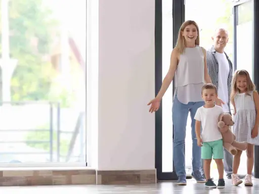Familia de 4 miembros sonriendo y entrando a su nuevo hogar, pensando en el consumo medio electricidad.