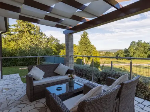 Muebles de mimbre y mesa de cristal en una terraza grande con vistas al campo. Ideas para como decorar una terraza grande con estilo y comodidad.