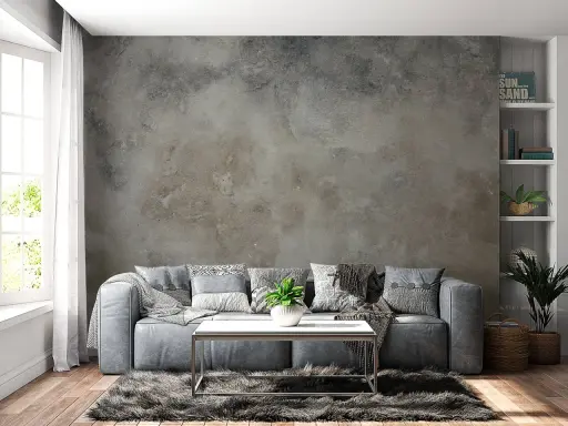 Sofá gris frente a una pared con efecto de pintar pared efecto envejecido. Alfombra peluda y mesa de centro metálica.